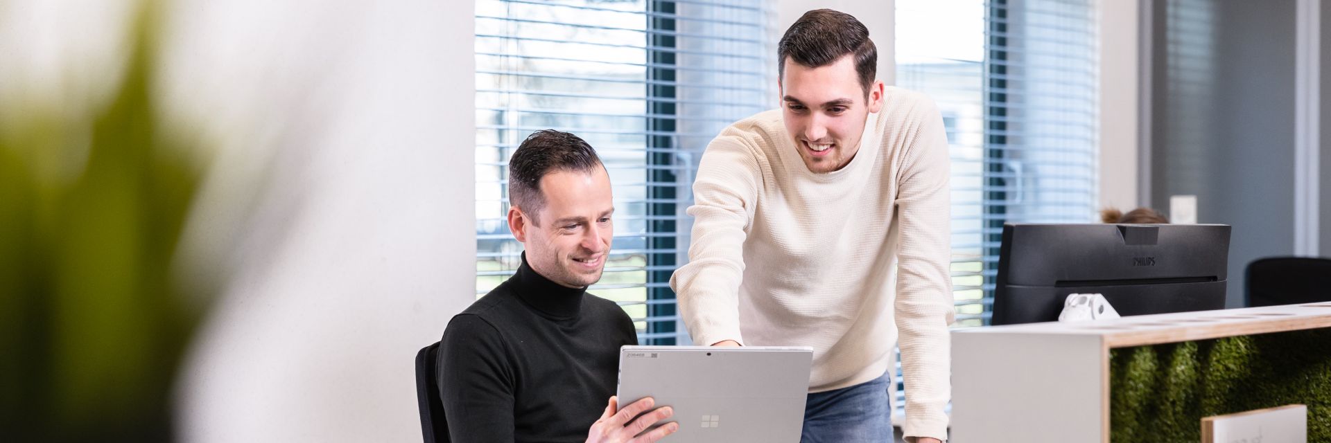 Twee mannelijke medewerkers aan bureau met tablet
